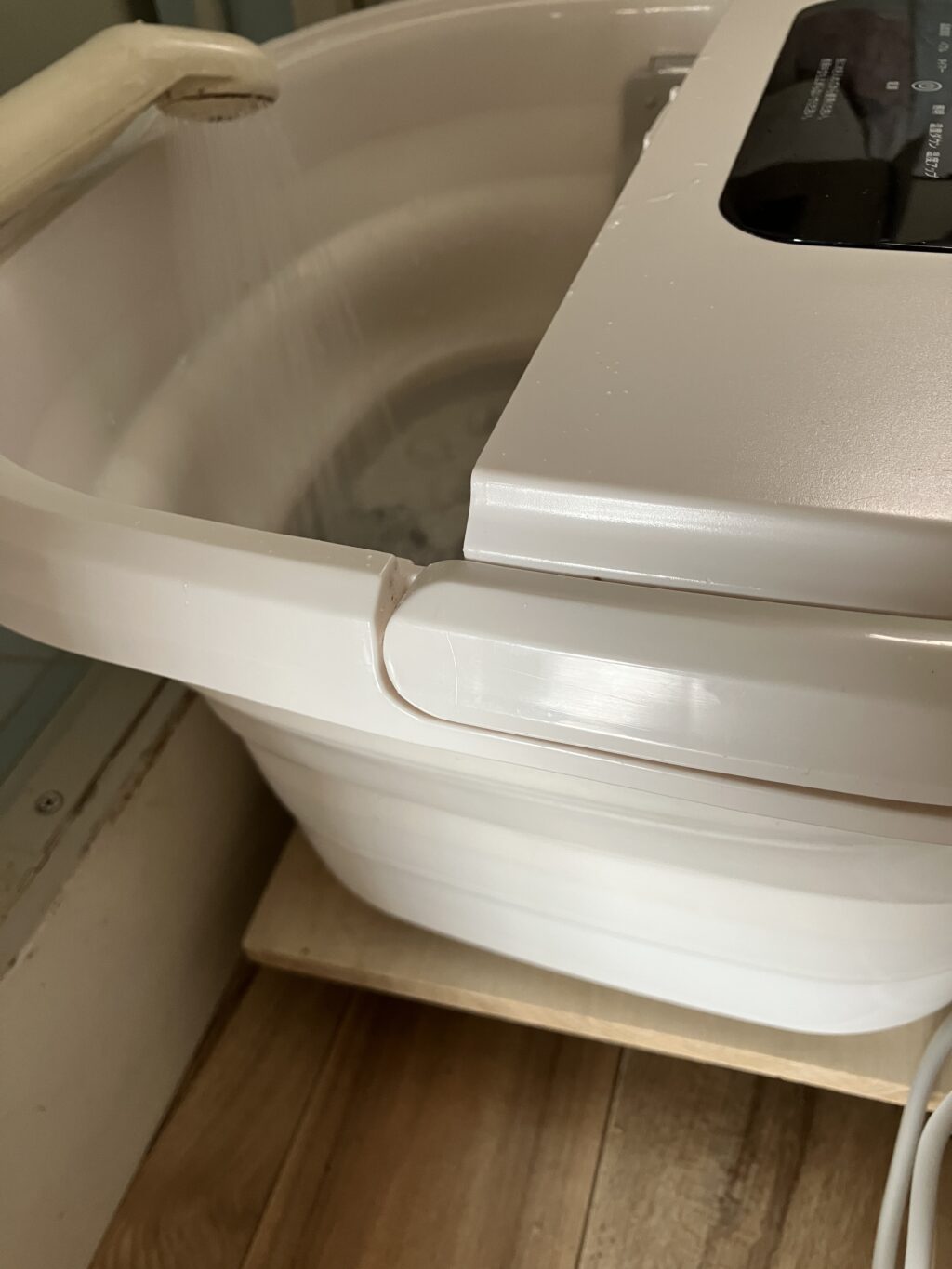 浴室の脇でフットバスにお湯を入れている様子