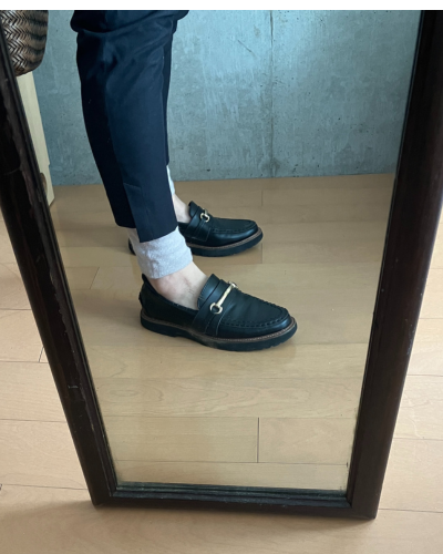 黒い短めの細身ジーンズの下にレッグウォーマーを着用して、素足にローファーを履いた様子（横から）