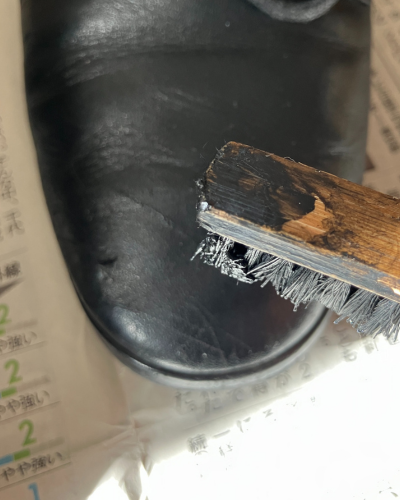 補色クリームをのせたブラシでショートブーツを補修しようとしている様子