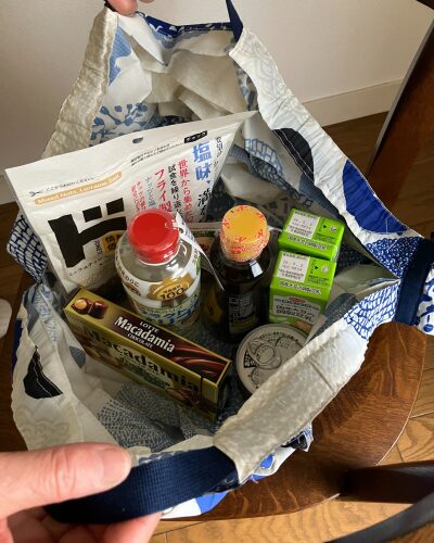 マーナのエコバッグ「シュパット」を広げて、品物を上に置いて、取っ手部分を持ち上げる様子