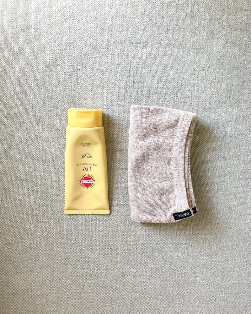 折りたたんだBSファインのレッグウォーマーを、日焼け止めと並べて大きさを比較している様子