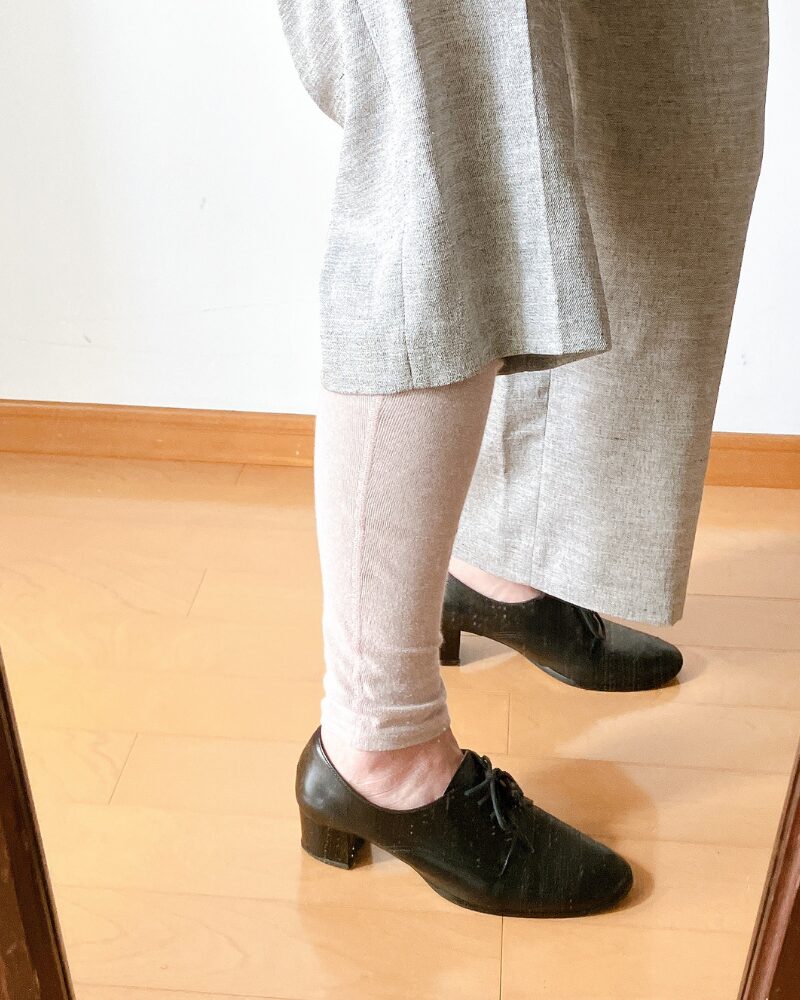 スラックスの下に履いたレッグウォーマーを見せている様子
